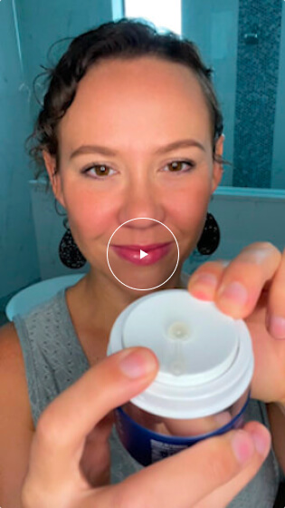 A woman with curly hair holds a blue jar of Cellular Hydration Serum, about to press the pump